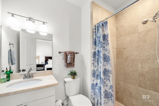 ensuite bathroom with toilet, tiled shower, and vanity
