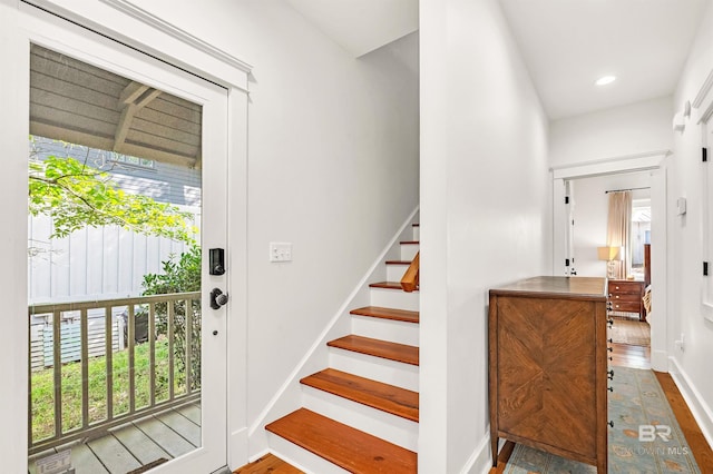 stairs with baseboards, wood finished floors, and recessed lighting