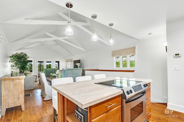 kitchen featuring electric stove, brown cabinetry, light wood-style floors, decorative light fixtures, and a center island