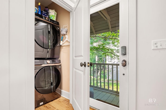 washroom featuring estacked washer and dryer, wood finished floors, and baseboards