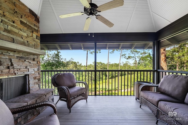 sunroom with ceiling fan, healthy amount of natural light, and an outdoor living space with a fireplace