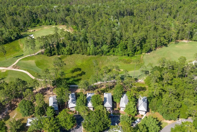 aerial overview of property's location featuring a forest and a local golf course