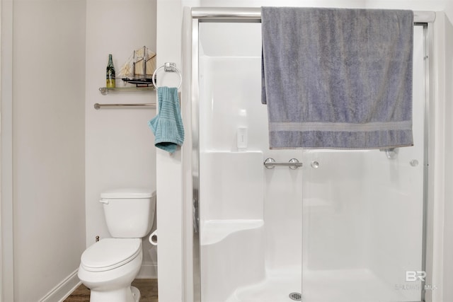 full bathroom featuring a stall shower, baseboards, and toilet