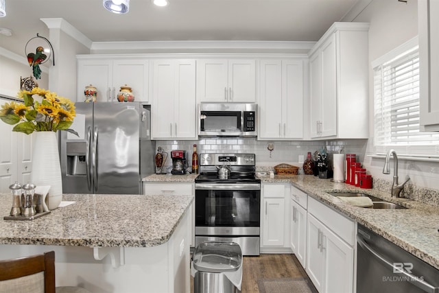 kitchen with white cabinetry, stainless steel appliances, ornamental molding, and a sink
