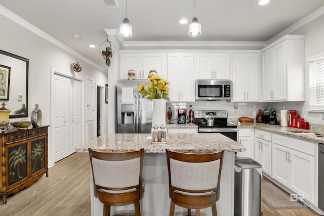 kitchen featuring stainless steel appliances, crown molding, white cabinetry, decorative backsplash, and a center island