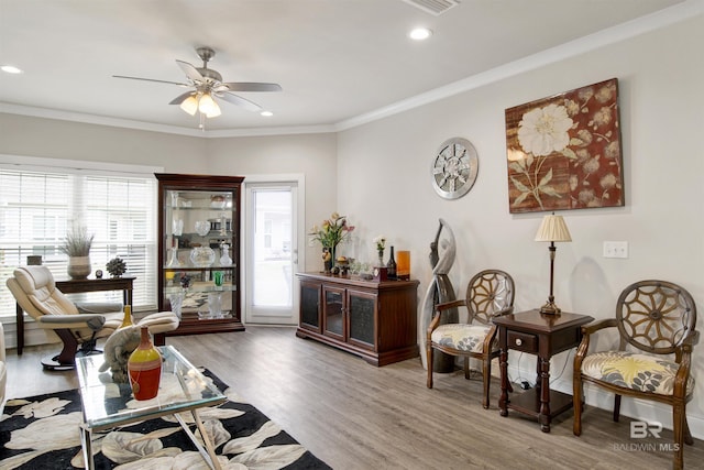 sitting room featuring a wealth of natural light, ornamental molding, ceiling fan, and wood finished floors