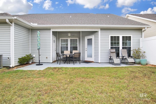 rear view of property featuring a lawn, a patio, roof with shingles, and ceiling fan