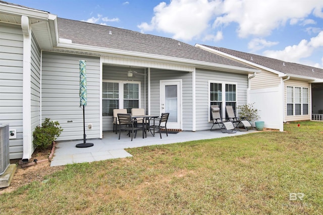 rear view of property featuring a yard, a patio area, a shingled roof, and a ceiling fan