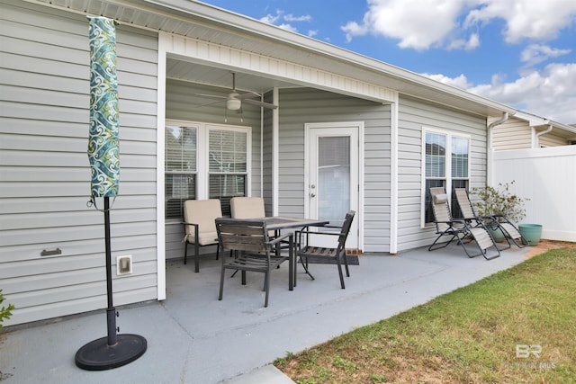 view of patio featuring outdoor dining area, ceiling fan, and fence