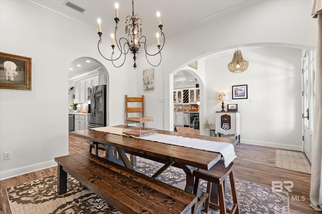 14281 Timber Ridge Dr, Loxley, AL 36551 - dining room with a chandelier, light wood-type flooring, crown molding, arched walkways, and recessed lighting