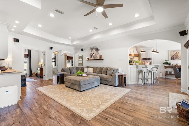 14281 Timber Ridge Dr, Loxley, AL 36551 - living area featuring arched walkways, a raised ceiling, a ceiling fan, light wood-style floors, and crown molding