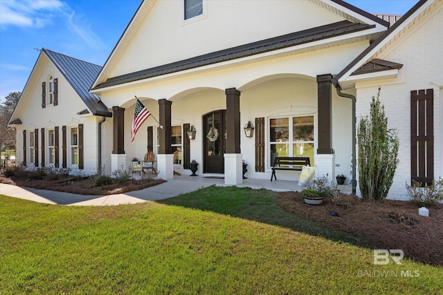 14281 Timber Ridge Dr, Loxley, AL 36551 - view of front of property with covered porch, brick siding, a front yard, and a standing seam roof