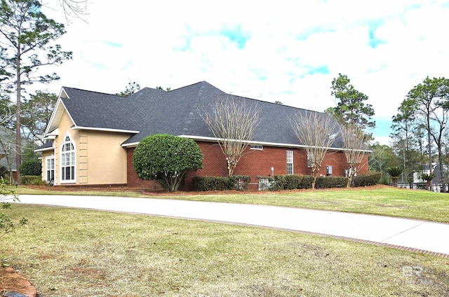 view of front of house featuring brick siding, stucco siding, a shingled roof, and a front yard