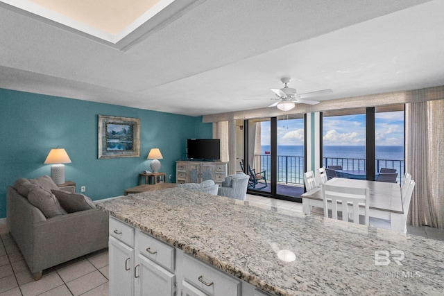24132 Perdido Beach Blvd Unit 1081, Orange Beach, AL 36561 - kitchen featuring open floor plan, white cabinetry, ceiling fan, light tile patterned floors, and light stone counters