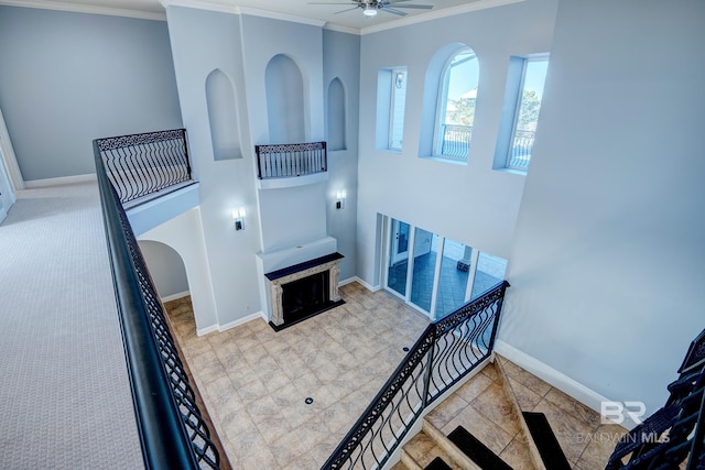 stairs featuring ceiling fan and crown molding