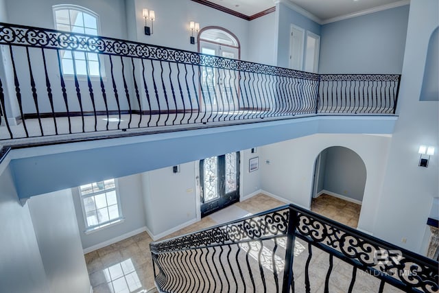 stairway featuring french doors, crown molding, and a high ceiling