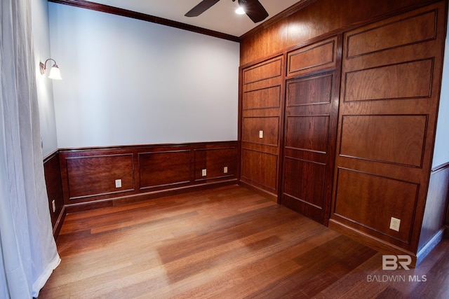 empty room featuring dark wood-type flooring, ceiling fan, and ornamental molding