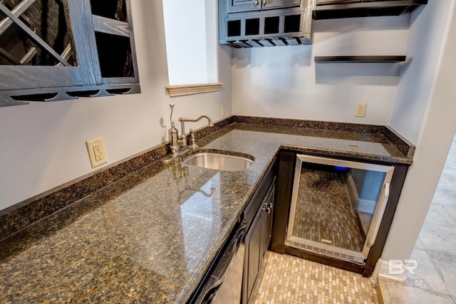 kitchen with dark stone countertops, light tile patterned floors, sink, and beverage cooler