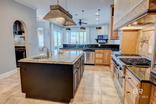 kitchen with dark stone countertops, ceiling fan, a center island with sink, and stainless steel appliances