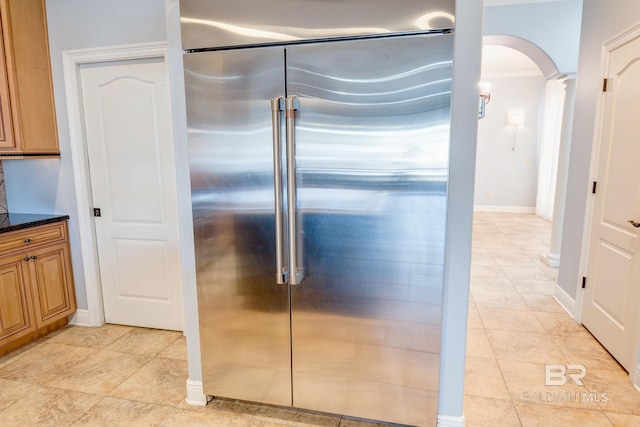 kitchen with high quality fridge, dark stone countertops, and ornate columns