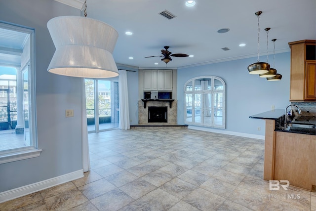 kitchen featuring pendant lighting, ceiling fan, crown molding, and sink