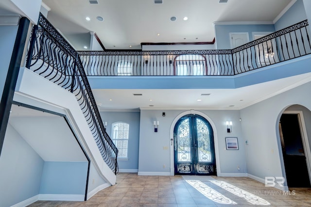 entryway with a towering ceiling, crown molding, and french doors