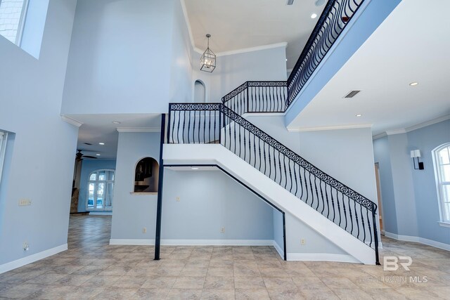 staircase featuring ceiling fan, a high ceiling, and ornamental molding