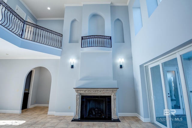 unfurnished living room with crown molding, a fireplace, and a high ceiling