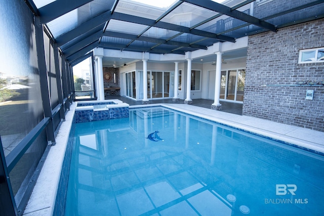 view of swimming pool with glass enclosure and an in ground hot tub