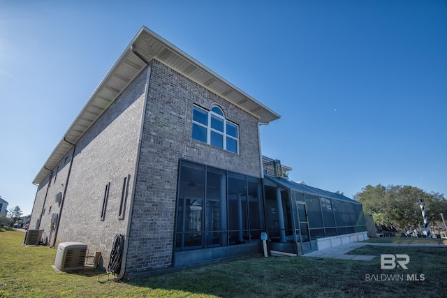 back of property featuring central air condition unit, a sunroom, and a yard