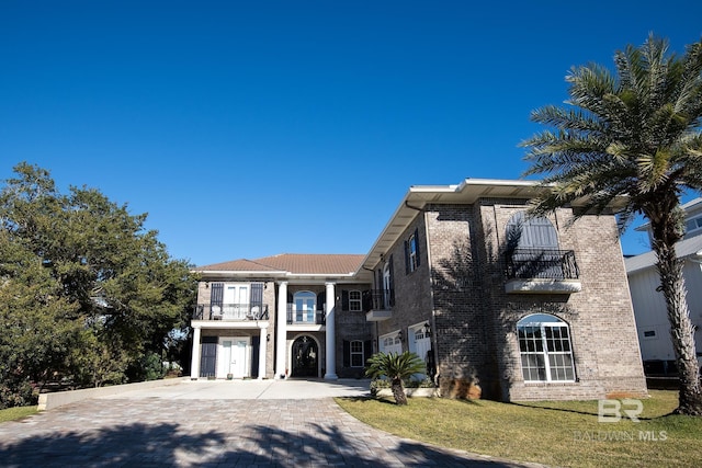 view of front of house featuring a garage, a balcony, and a front yard