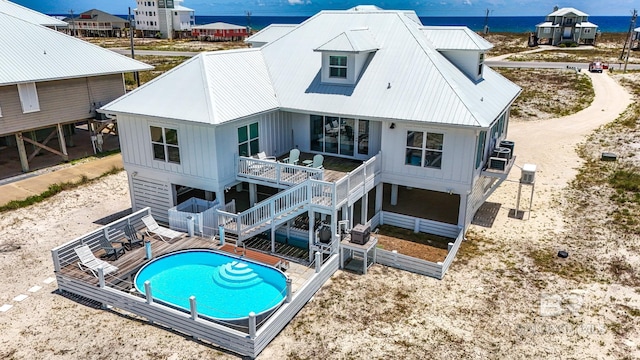2764 W Beach Blvd, Gulf Shores, AL 36542 - back of house featuring stairway, a deck with water view, board and batten siding, an outdoor pool, and a metal roof