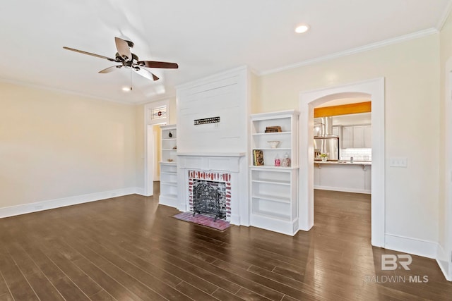 unfurnished living room with dark hardwood / wood-style floors, ceiling fan, ornamental molding, and a brick fireplace