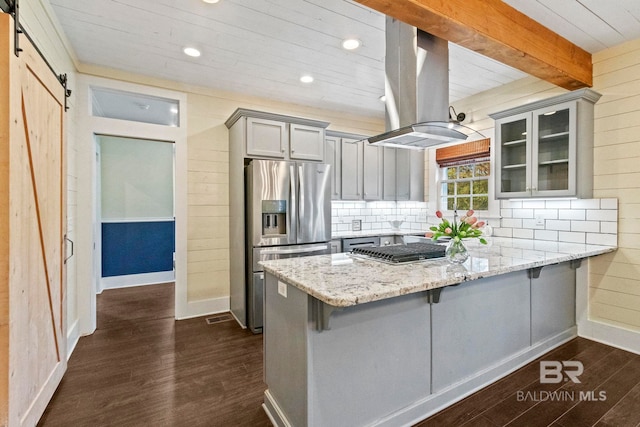 kitchen with island exhaust hood, gray cabinetry, stainless steel appliances, a barn door, and dark hardwood / wood-style floors