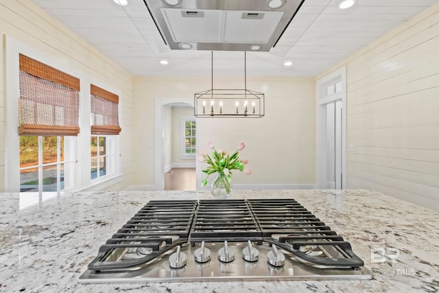 kitchen with decorative light fixtures, light stone counters, stainless steel gas cooktop, and a healthy amount of sunlight