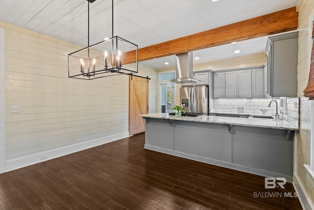 kitchen with pendant lighting, stainless steel fridge, a barn door, gray cabinets, and dark hardwood / wood-style flooring