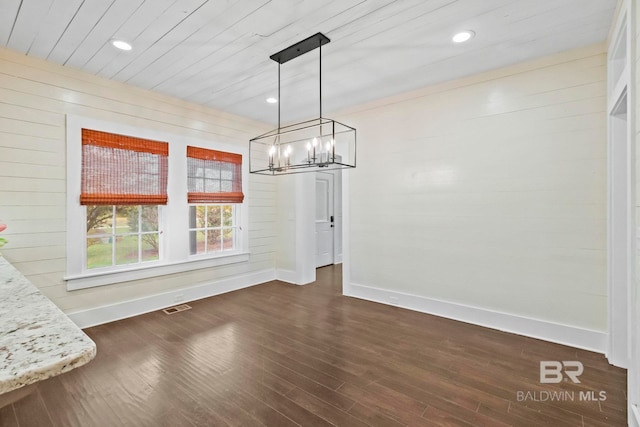 unfurnished dining area with a notable chandelier, dark hardwood / wood-style flooring, wood ceiling, and wooden walls