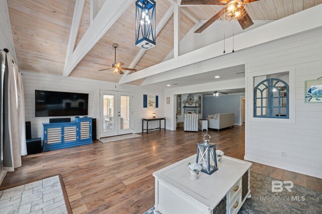 living room featuring beam ceiling, french doors, dark wood-type flooring, wooden ceiling, and wooden walls