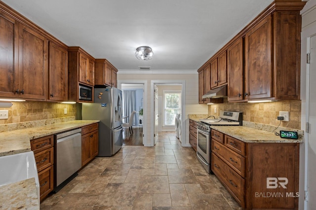 kitchen with decorative backsplash, light stone counters, ornamental molding, and appliances with stainless steel finishes