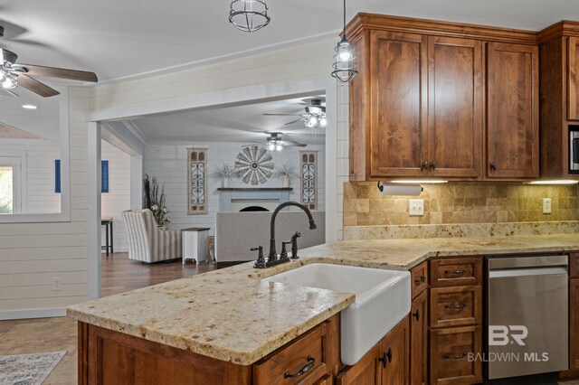 kitchen featuring appliances with stainless steel finishes, backsplash, light stone counters, sink, and hanging light fixtures