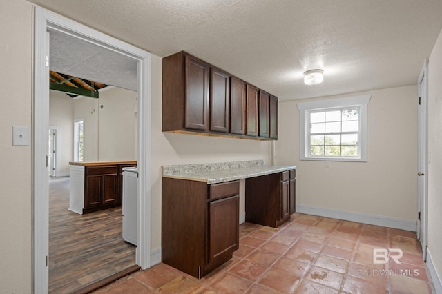 kitchen with dark brown cabinets, a textured ceiling, and washer / dryer