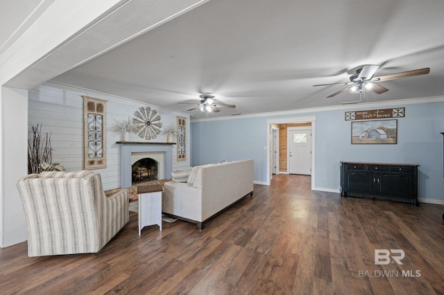 living room with a fireplace, dark hardwood / wood-style floors, ceiling fan, and ornamental molding