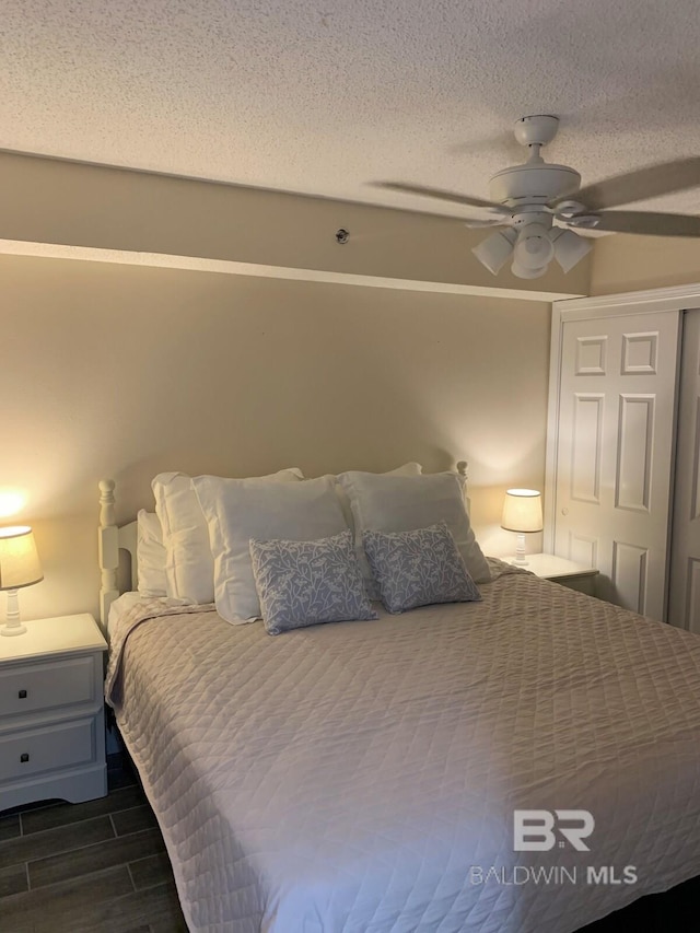 bedroom with dark hardwood / wood-style flooring, ceiling fan, and a textured ceiling