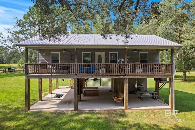 rear view of property with ceiling fan, a wooden deck, a patio area, and a lawn