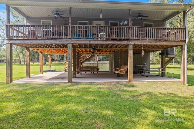 back of house with ceiling fan, a lawn, a wooden deck, and a patio area