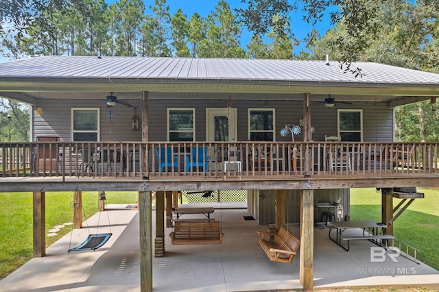 back of property with a wooden deck, ceiling fan, a patio, and a yard