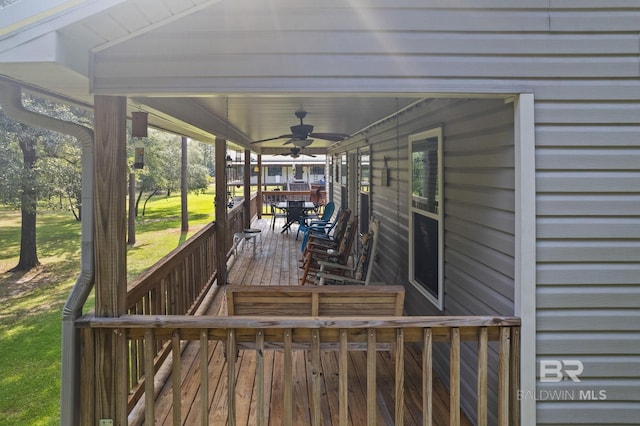 wooden terrace featuring a ceiling fan and a lawn