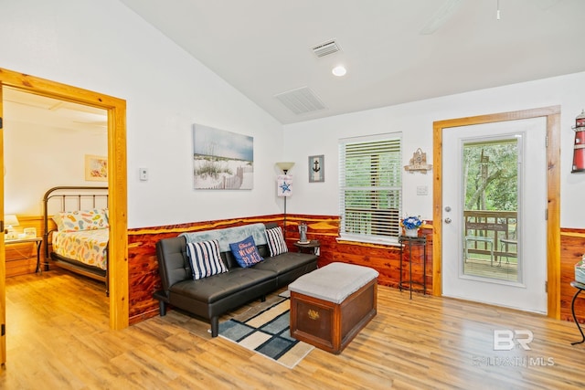 living room featuring wood finished floors, vaulted ceiling, and wainscoting