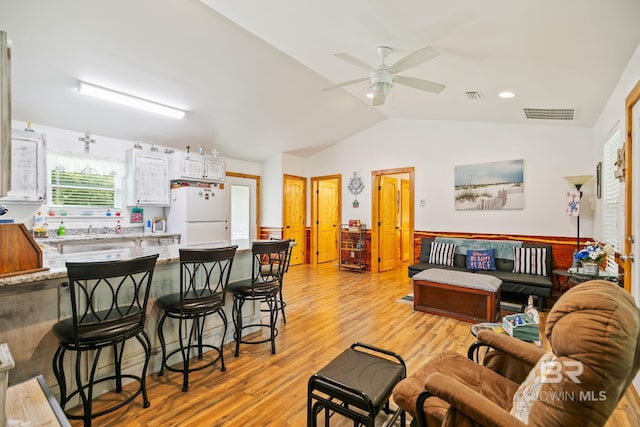 living room featuring ceiling fan, sink, light wood-type flooring, and vaulted ceiling