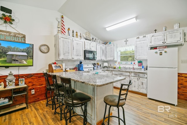 kitchen featuring white appliances, vaulted ceiling, white cabinets, and light wood-type flooring